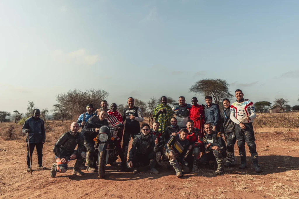 Grupo de pilotos y guías posando sobre tierra roja con acacias al fondo